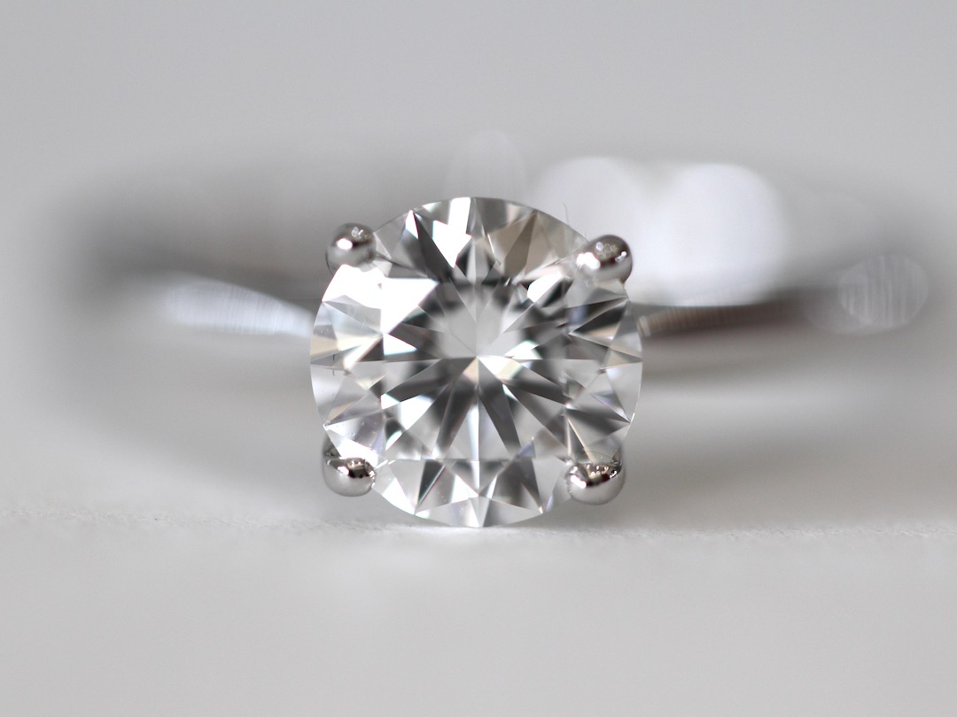 close up zoom of round diamond set on 4 prong solitaire engagement ring