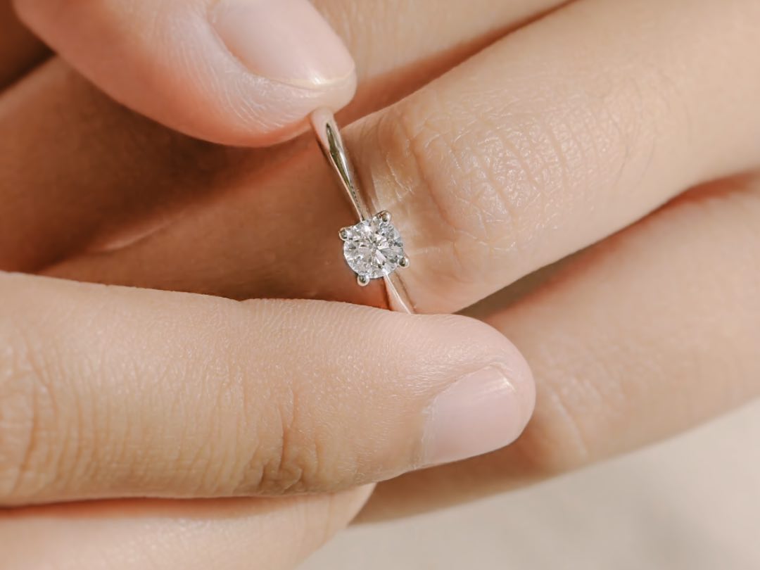 two fingers wearing solitaire diamond ring