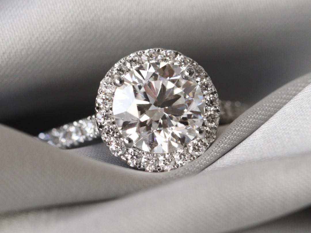 1 carat halo diamond ring close up lay flat front on gray satin 